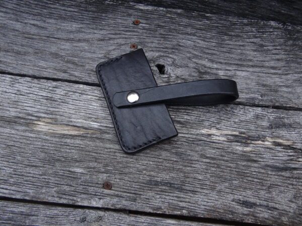 A black wallet laying on top of a wooden table.