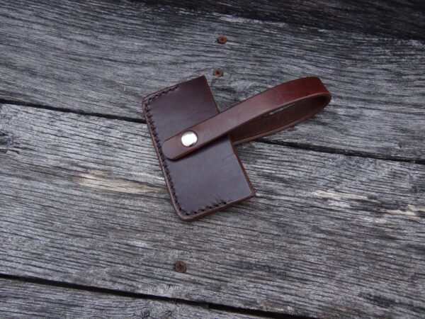 A brown leather wallet laying on top of a wooden surface.