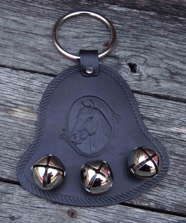 A leather key chain with three bells on it.