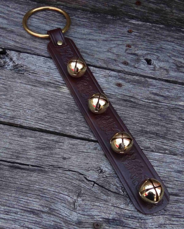 A brown leather key chain with four brass bells.