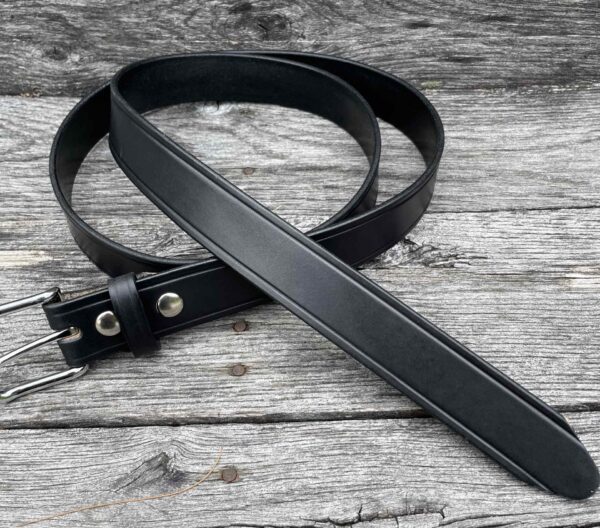 A black belt laying on top of a wooden table.