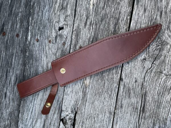 A brown leather knife sheath on top of a wooden table.