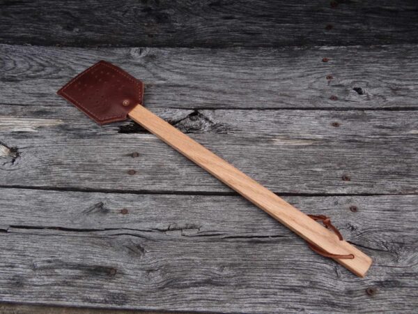 A wooden spatula with brown leather on it.