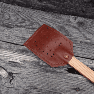 A wooden spatula with brown leather on it.