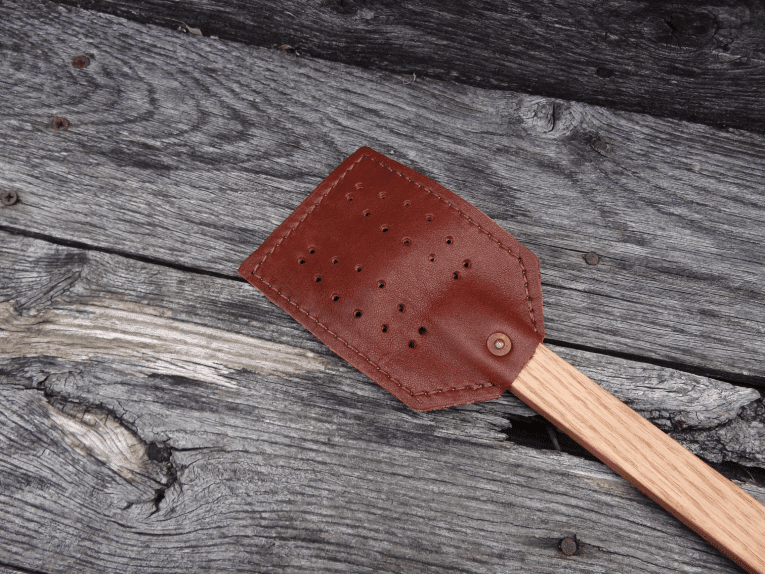 A wooden spatula with brown leather on it.