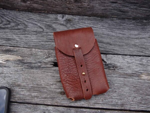 A brown leather case sitting on top of a wooden table.