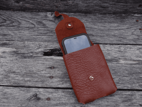 A red leather case with a phone in it.