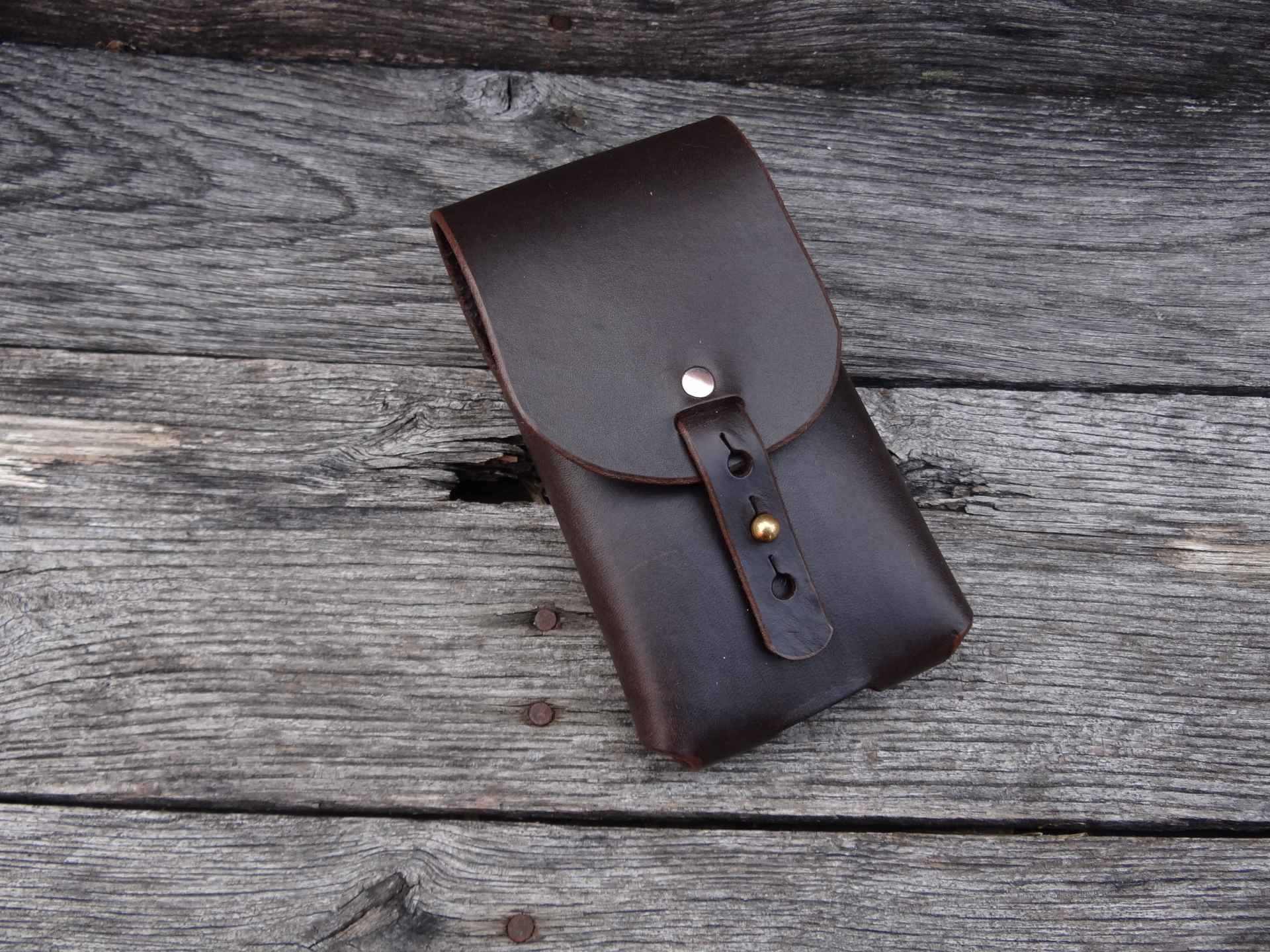 A brown leather case sitting on top of a wooden table.