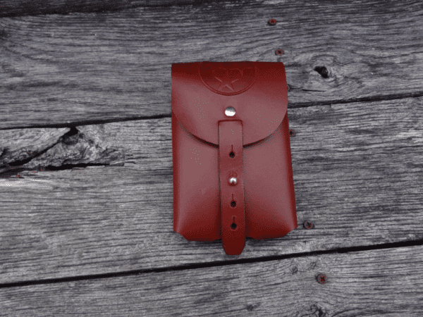 A red leather case sitting on top of a wooden surface.