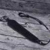 A black leather strap laying on top of a wooden surface.