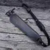 A black leather strap laying on top of a wooden table.