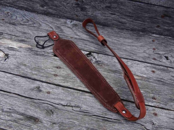 A brown leather strap laying on top of a wooden floor.