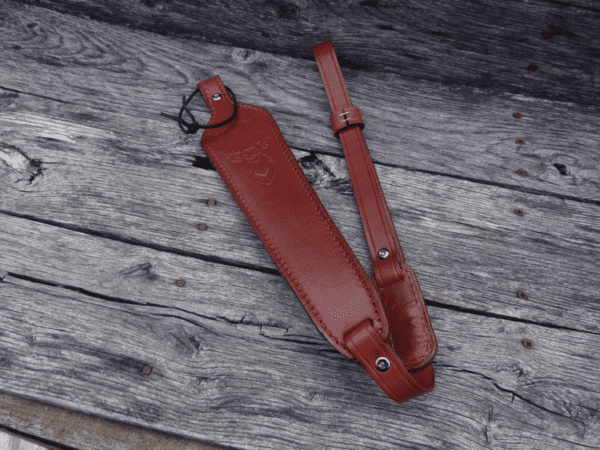 A red strap laying on top of a wooden table.