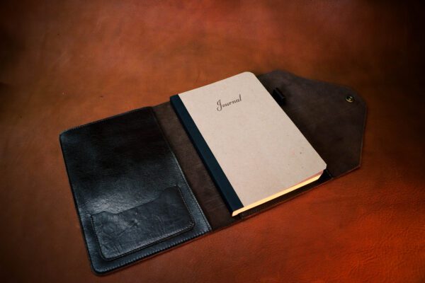 A notebook is sitting in an open leather case.