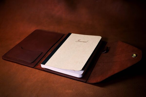 A notebook sitting on top of a brown leather case.