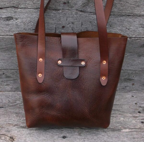 A brown leather bag sitting on top of a wooden floor.