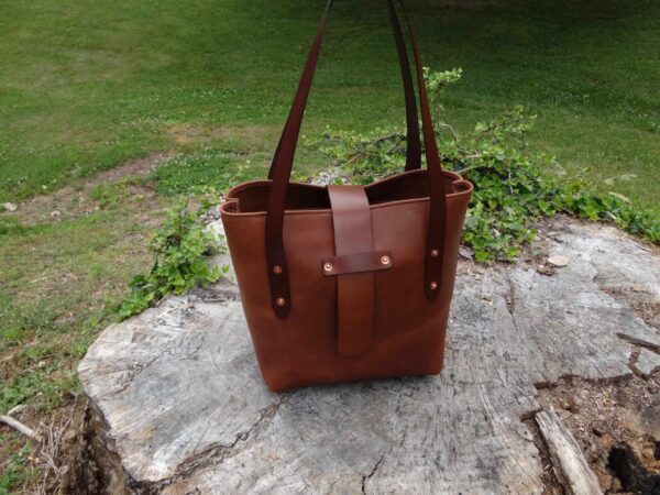 A brown leather bag sitting on top of a rock.