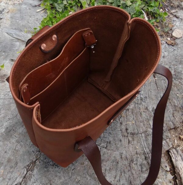 A brown purse sitting on top of a cement ground.