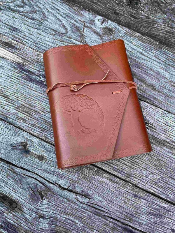 A brown leather book sitting on top of a wooden table.