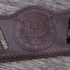 A brown leather belt with an eagle on it.