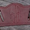 A leather belt with an american flag and spartan helmet on it.