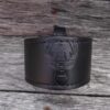 A black leather bracelet with a picture of a crown on it.