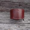 A brown leather bracelet sitting on top of a wooden table.