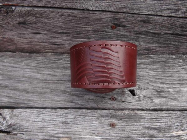 A brown leather bracelet sitting on top of a wooden table.