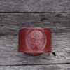 A red leather bracelet with three stars on it.