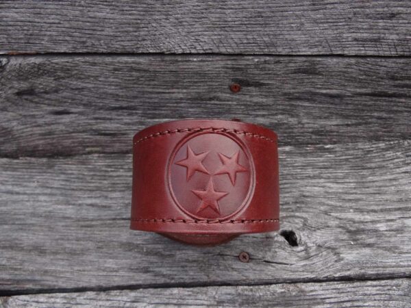 A red leather bracelet with three stars on it.