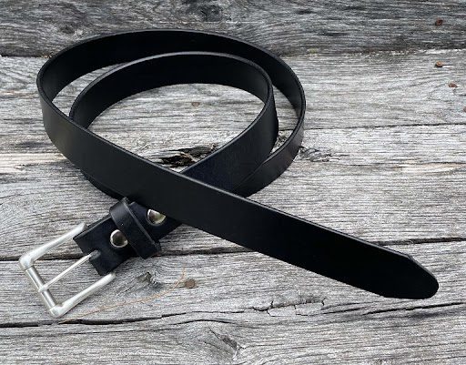 A black belt laying on top of a wooden table.