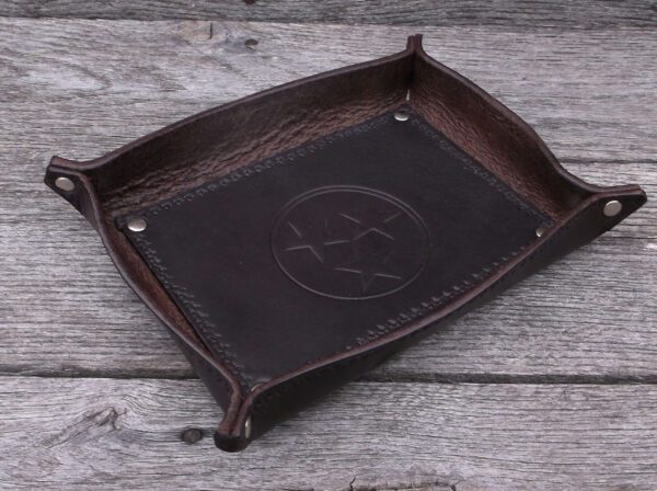 A brown leather tray sitting on top of a wooden table.