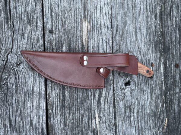 A brown leather knife sheath on top of a wooden surface.