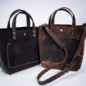 Two bags of leather are sitting next to each other.