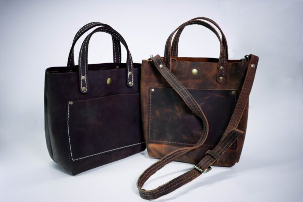 Two bags of leather are sitting next to each other.