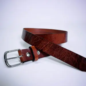 A brown leather belt with silver buckle on top of white surface.